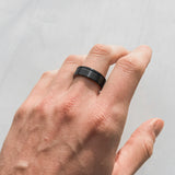 isolated hand wearing a whiskey barrel and tungsten mens wedding ring